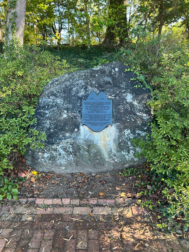 A bronze plaque attached to a boulder.