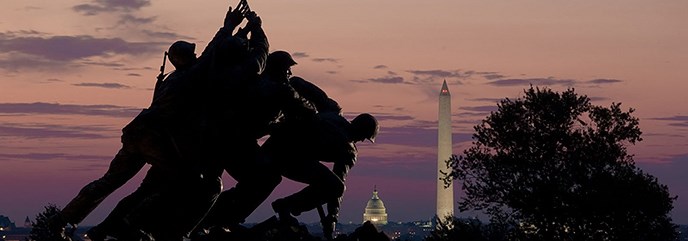 Large bronze statue of six men raising a US flag with sunset and Washington, DC in the background