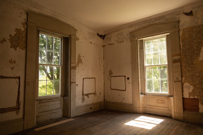 An empty room in a historic building with two large windows.