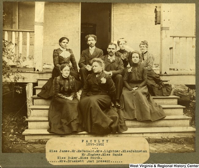 early 1900s image of six women and two men sitting on the steps of a building