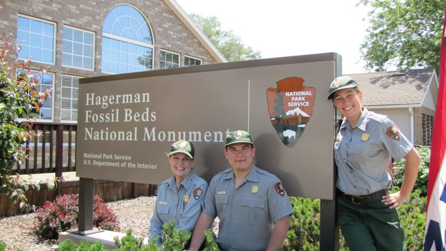 summer uniformed workers near visitor center sign