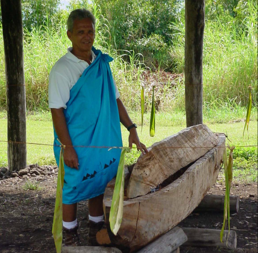 a man stands next to a small wooden canoe