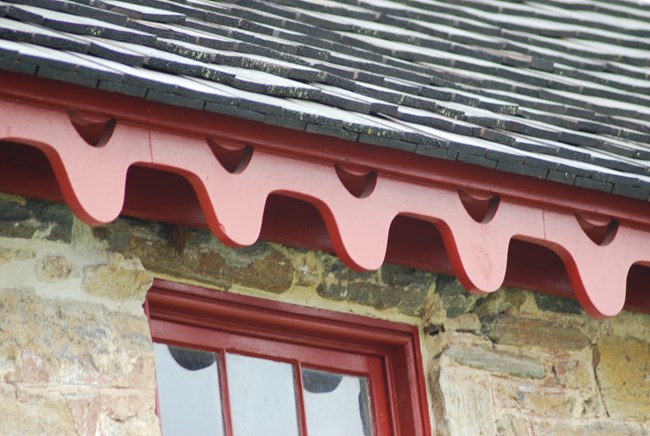 Red Barge Board running along the roof, above the stone structure.