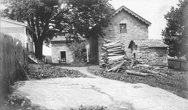 a black and white photograph of the slave quarters with children standing in the doorway.