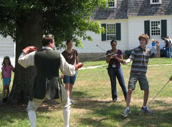 A park visitor engages in swordsmanship with an instructor.