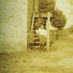 3 children sitting on stairs near a barn