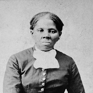 black and white image of African American woman looking at the camera, wearing a dark dress and white collar ruffle