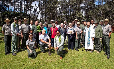 A group of park rangers and communities members standing on green grass