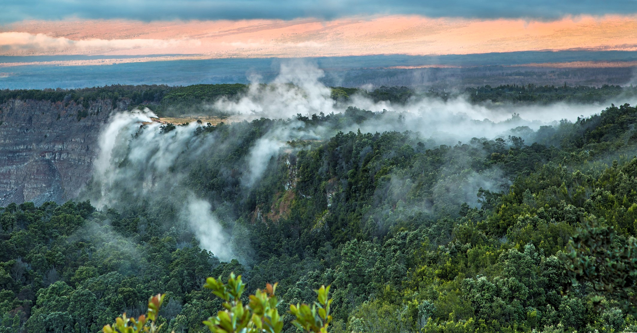 Steam rising from the forested edge of a volcanic crater