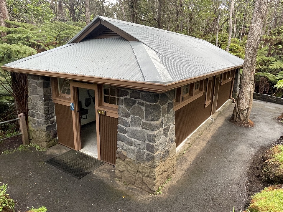 A single story stone and wood restroom in a forest