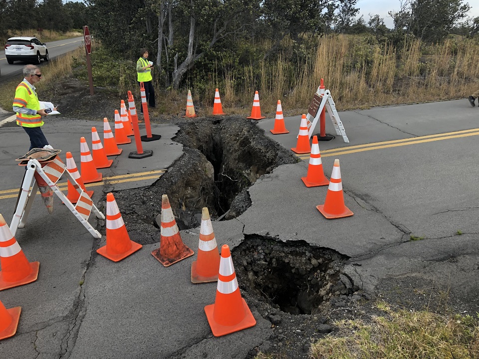 Workers contemplate earthquake damage to road