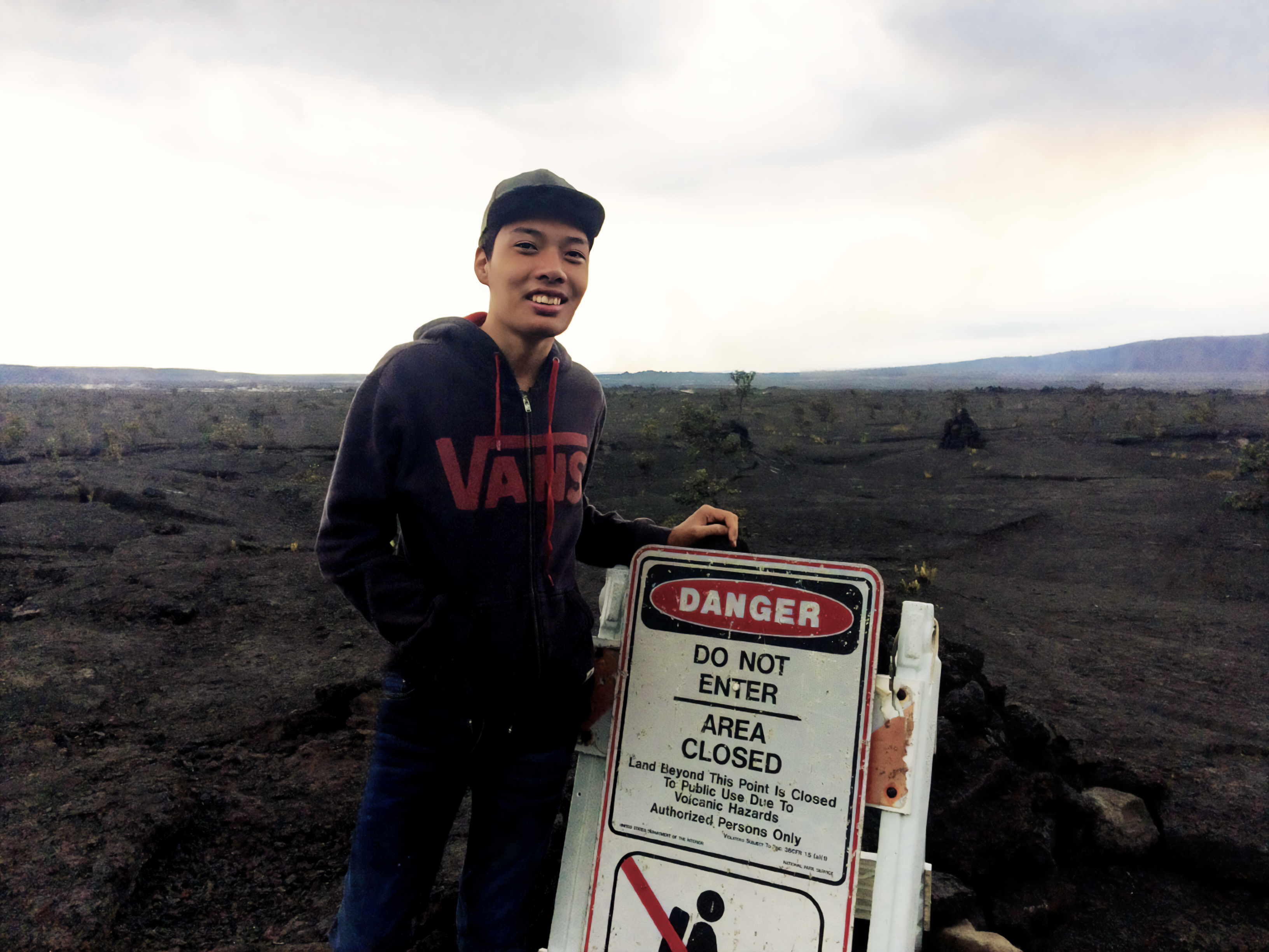 Visitor stands behind closure sign enjoying views of the caldera