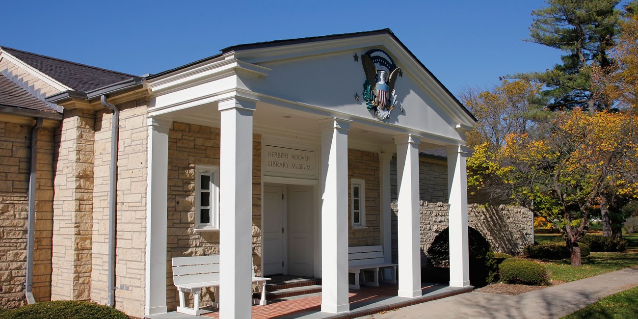 A white museum portico has a presidential seal mounted on the pediment.