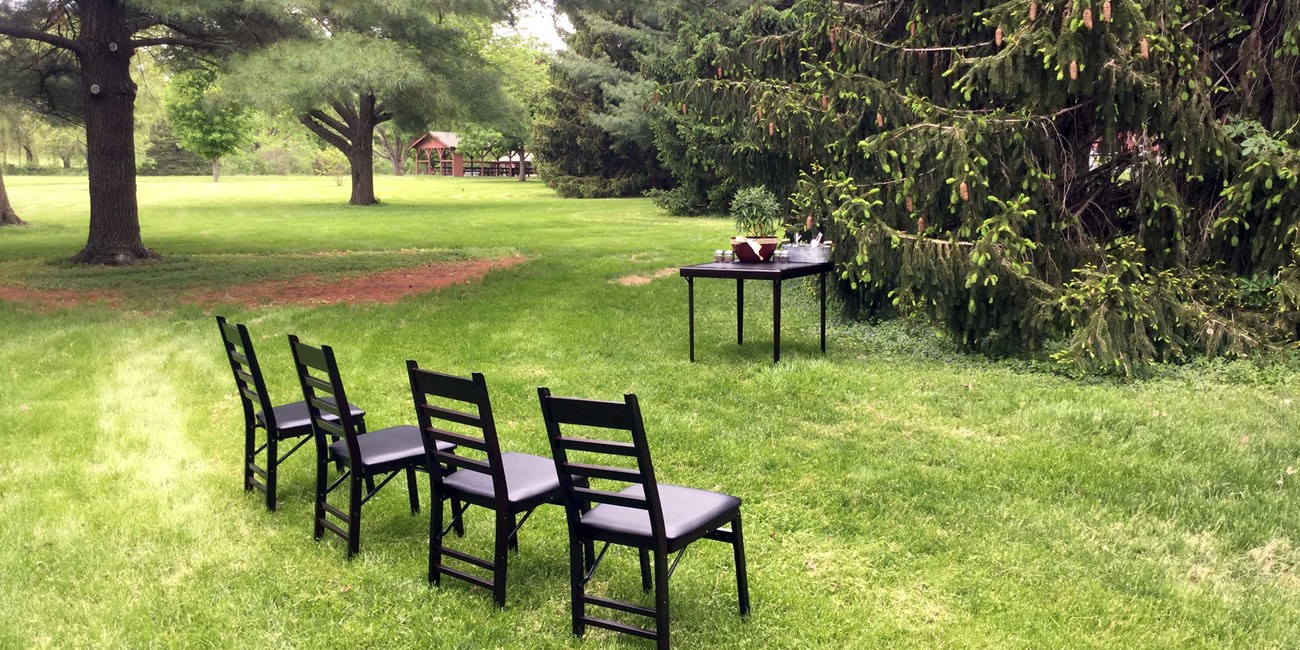 Four chairs facing a small table await an outdoor wedding ceremony.