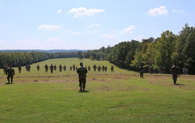 Enlisted military personnel walking away from camera through the battlefield