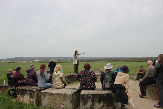 a park ranger speaks to a group of visitors outdoors.