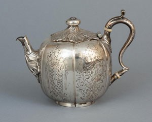 A silver teapot engraved with floral decoration.