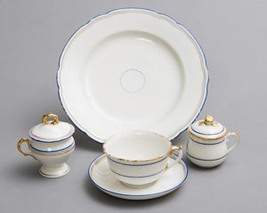 A set of white china with narrow blue and gold bands on the rim.