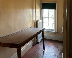 A narrow room with window and folding table attached to the wall.