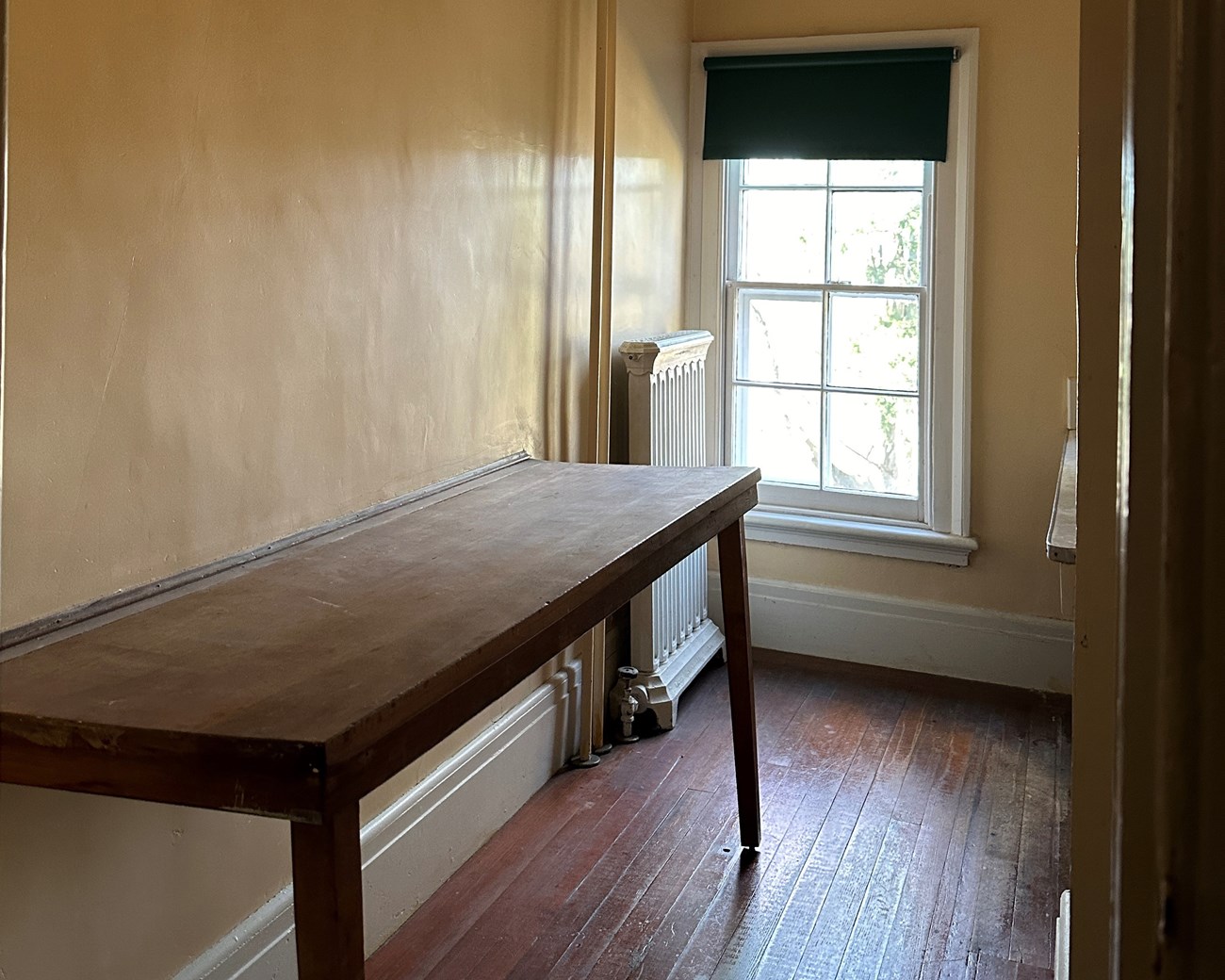 A narrow room with window and folding table mounted to the wall.