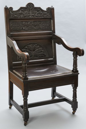 A carved wooden arm chair with leather padded seat.