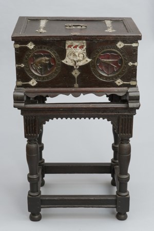 An elaborate carved oak box on a stand.