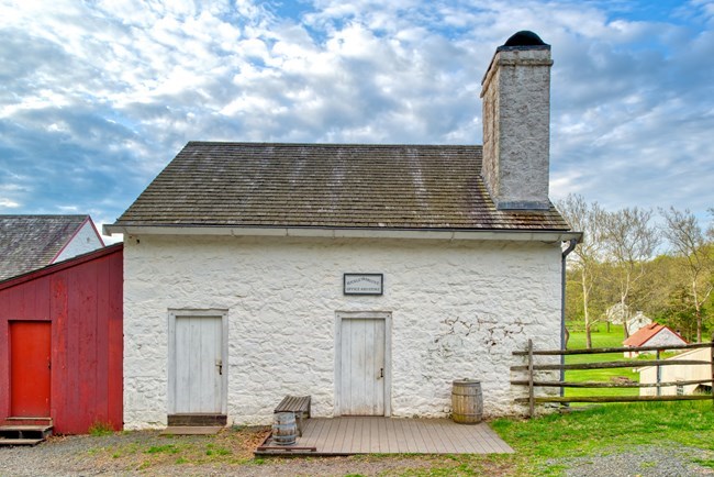 White building with 2 and a half floors with red shed attached.