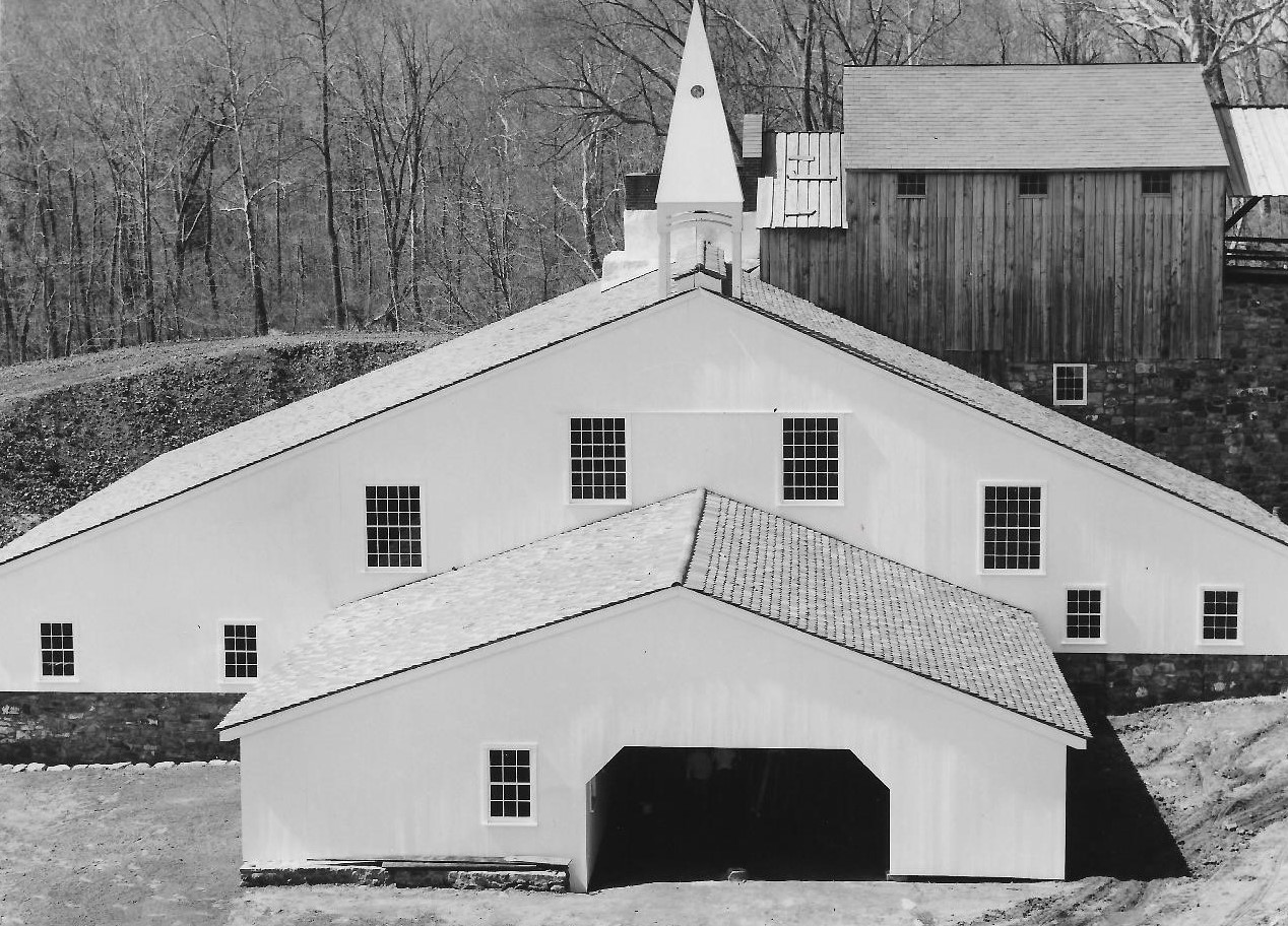 Black and white photograph of large building with triangular roof.