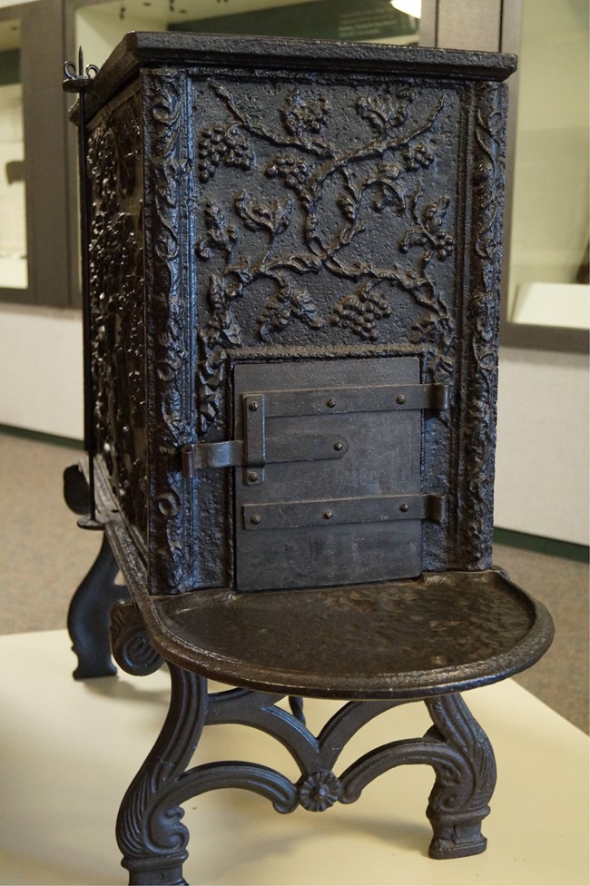 Iron stove with decorative floral and leaf design.