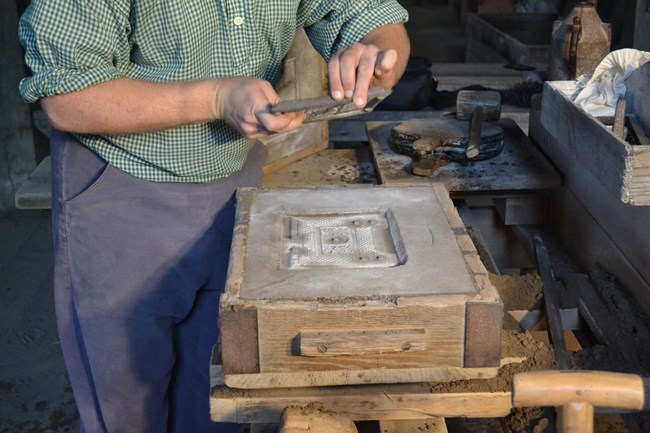 NPS Staff demonstrates the process of sand moulding