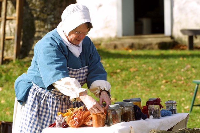 Hopewell Furnace Living History volunteer demonstrating how fabric was dyed
