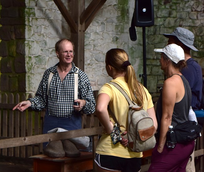 A historical reenactor speaks with a group of visitors.