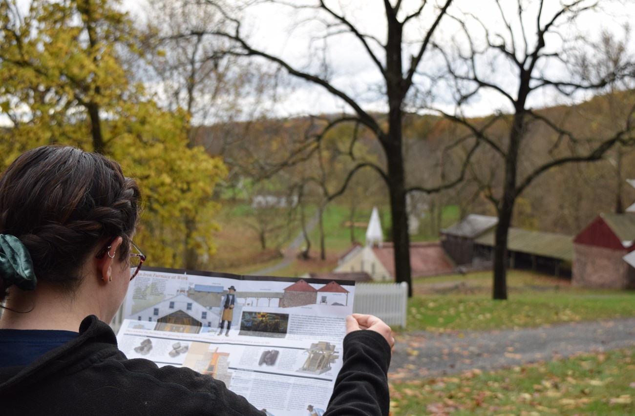 Visitor reading brochure with historic buildings in foreground