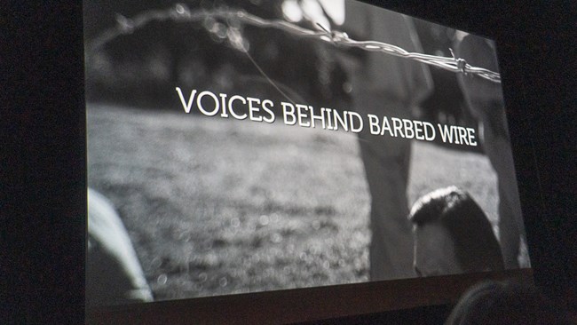 Voices Behind Barbed Wire title of movie on movie screen.
