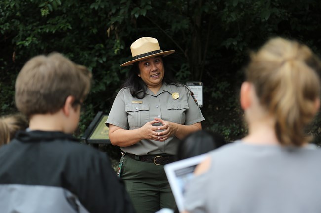 A female ranger is delivering a program to a group of children.