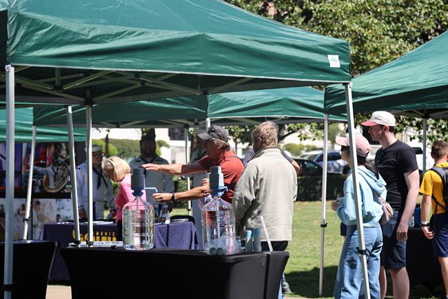 Attendees pump spring water into drinking cups.