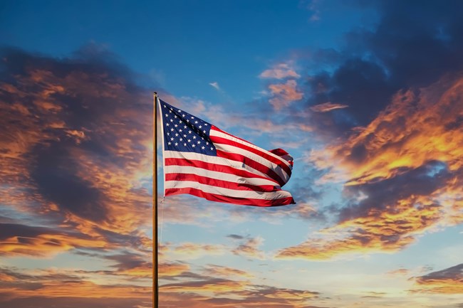 American Flag flutters in the air with sunset clouds in the background