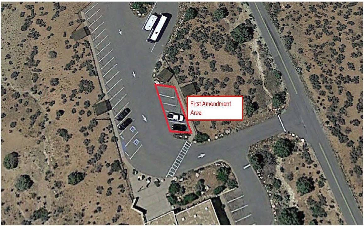 A satellite view of a parking lot with a red outlined area and "First Amendment Area" in text