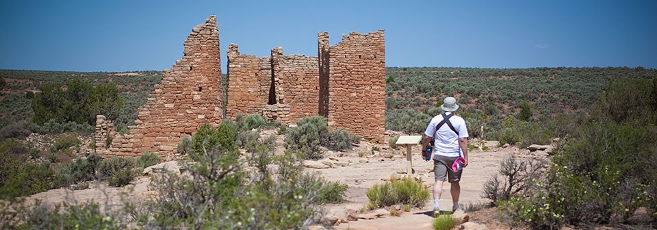 man walking toward ruin of stone structure