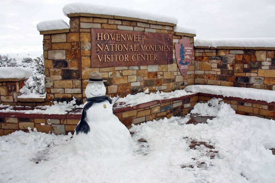 snowman decorated as a park ranger in front of the visitor center sign