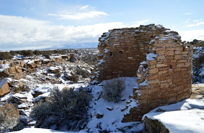 tower point ruin covered in snow with canyon and Sleeping Ute mountain in the background