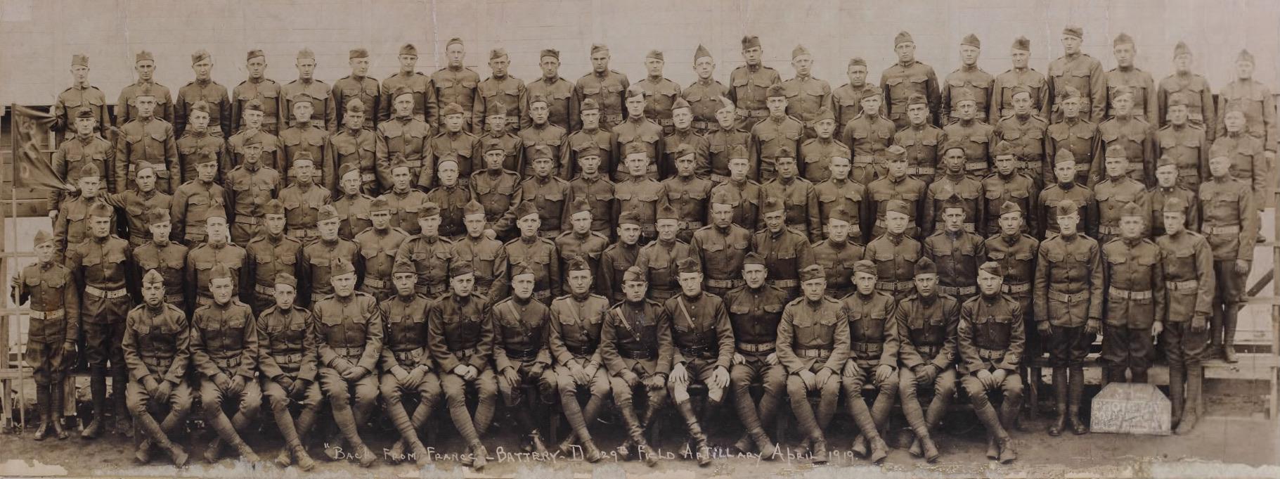 A large group of soldiers in uniform, from World War I, pose, including Harry Truman.