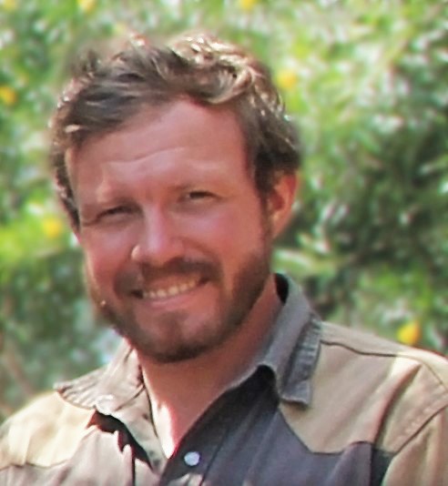 A bearded man wearing a brown shirt.