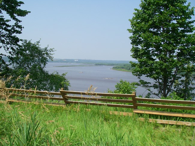 A view of the river beyond a fence line on a bluff
