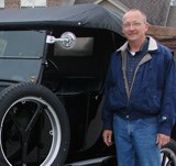 David G. Peitz alongside an antique vehicle