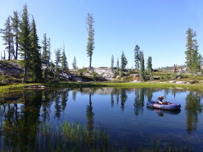 NPS staff member in a boat floating on lake at Lassen Volcanic NP