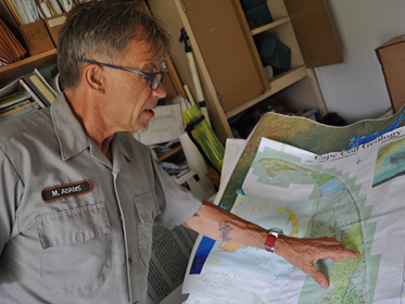 Scientist points to Cape Cod on a map in an office.