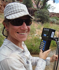 Woman with water quality meter smiles at camera