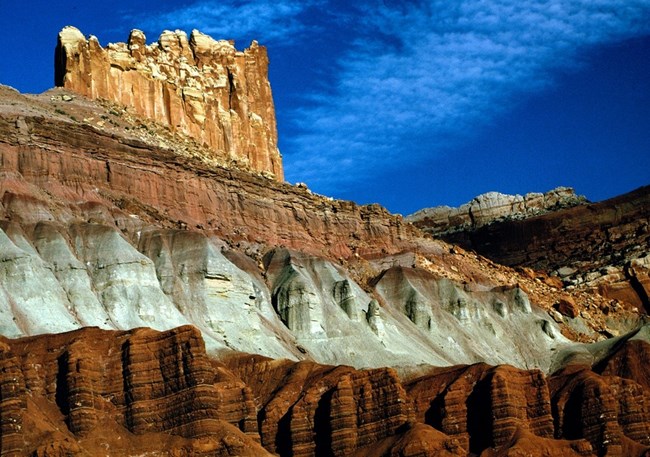 The Castle rises above striped red and gray rock layers under a deep blue sky.