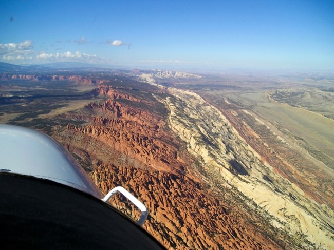 Aerial view of the Waterpocket Fold with tilted rock layers and narrow valleys looking north.
